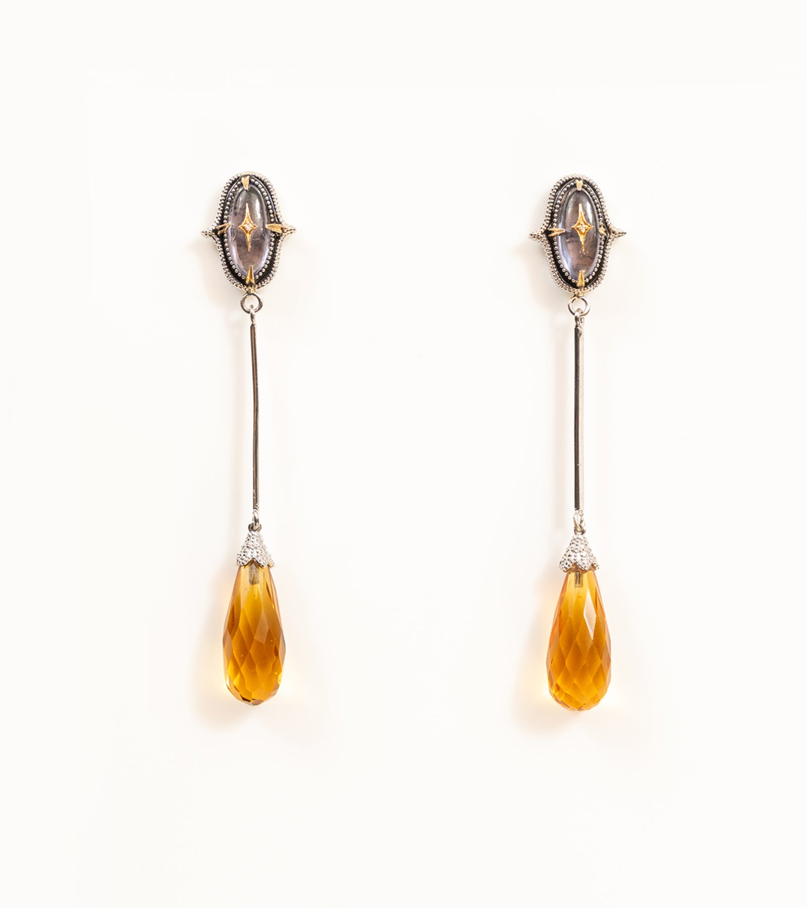 Meeti Earrings with an amethyst stud, gold star motif, long silver bar, and faceted topaz briolette drop
