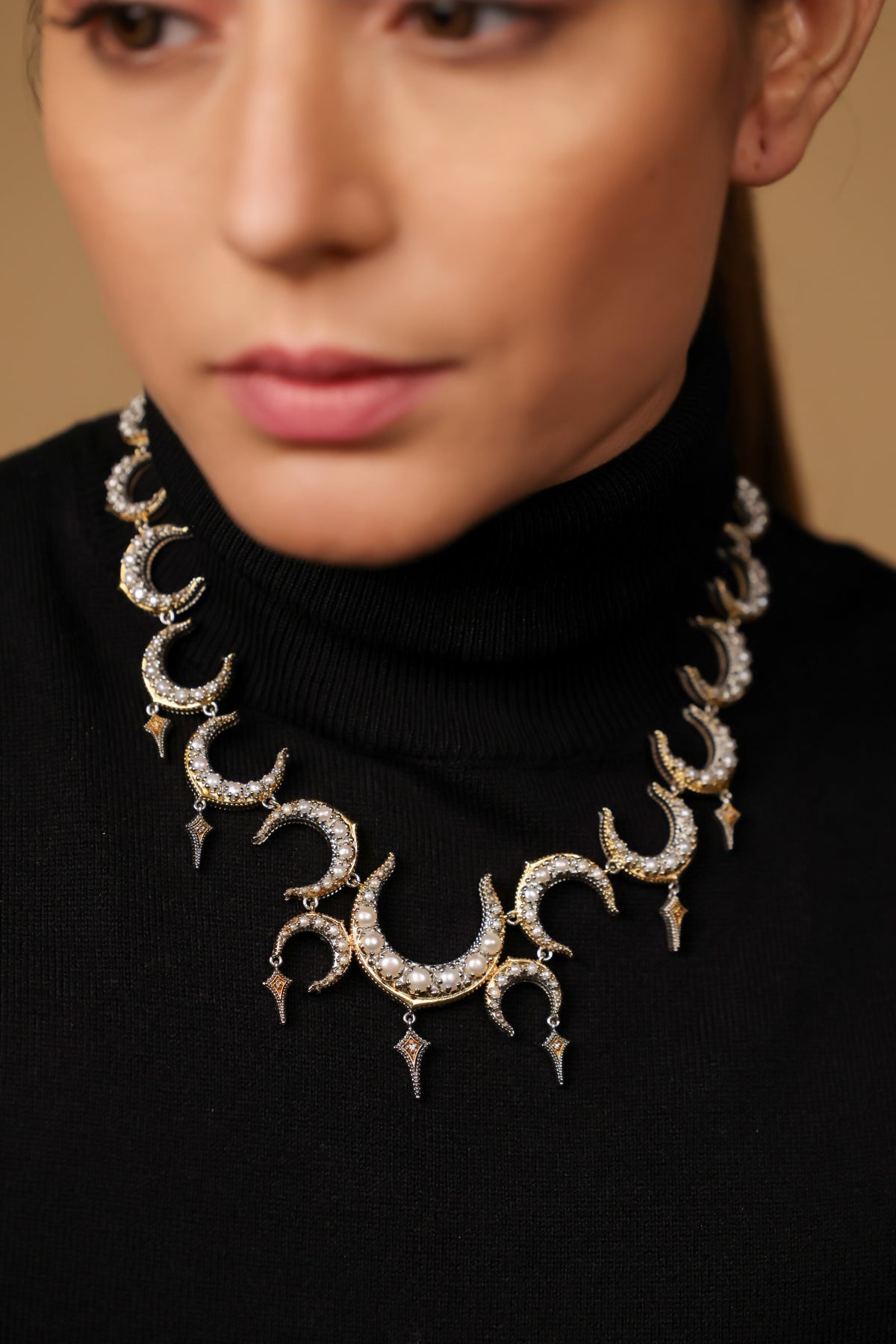 Close-up of the crescent silhouette and black enamel detailing on the Ragini Necklace